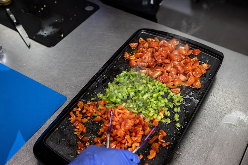 Barbara Weeks cooks bell peppers and tomatoes for grilled chicken flatbread during a free...