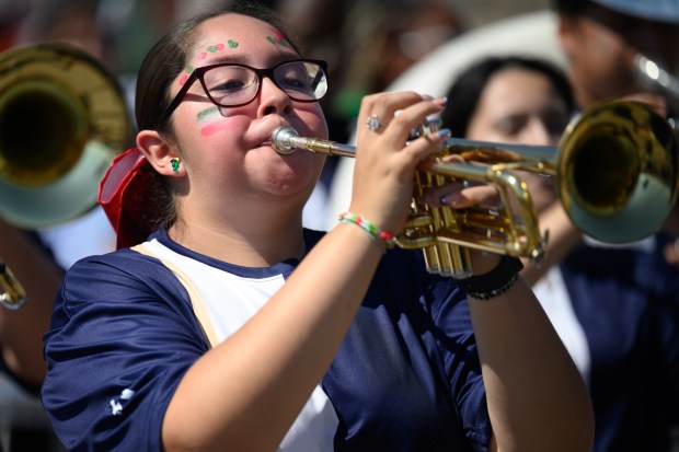 A Bishop Noll marching band member, wearing face paint in colors of the Mexican flag, plays the trumpet during the 101st annual Fiestas Patrias parade on Sunday, Sept. 14, 2025. (Kyle Telechan/for the Post-Tribune)