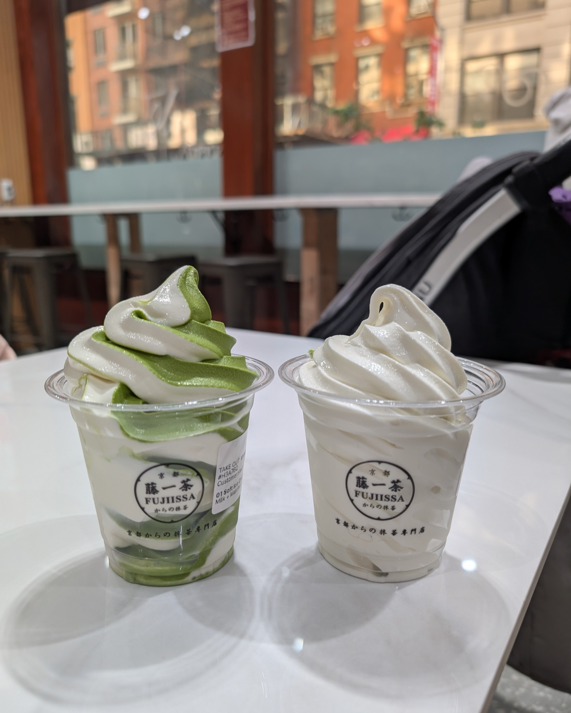 Two cup of soft serve, one a white and green swirl and one totally white.