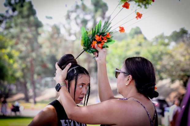 Cindy Hoffman puts a flower head-piece on her daughter Ava before performing with the HIVA Dance Foundation during the Pacific Islander Festival at Ski Beach on Mission Bay on Saturday, Sept. 2025. The festival featrured foodbooths, atras and craftes booths and performers form several Pacific Island Nations. ( Photo by Sandy Huffaker for The San Diego Union-Tribune)