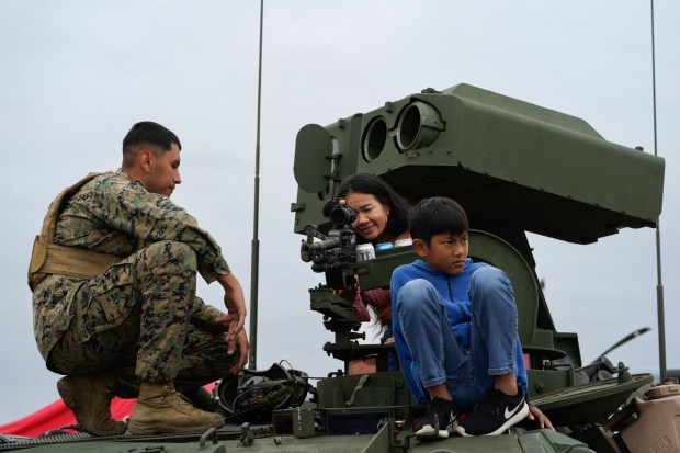 On top of his LAV (Light Armored Vehicle), LCpl Isaiah Gutierrez allows aviation fans to look through the gun scope mounted on a M240 machine gun, mounted on the rooftop of the LAV. The event which includes aerial vintage aircraft, displays and immersive experiences runs through Sunday. (Nelvin C. Cepeda / The San Diego Union-Tribune)