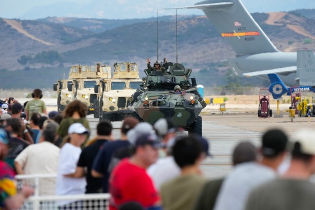 Following the demonstration of the Marine Air Ground Task Force (MAGTF), Marines drive their combat vehicles down the fight waving at the audience. The event which includes aerial vintage aircraft, displays and immersive experiences runs through Sunday. (Nelvin C. Cepeda / The San Diego Union-Tribune)
