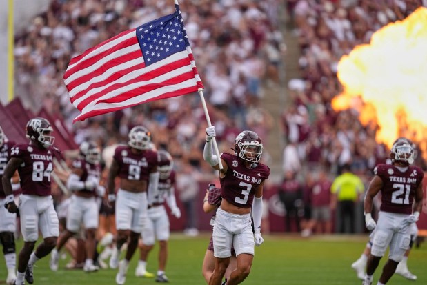 Texas A&M safety Marcus Ratcliffe (3) carries the American flag as the team enters the field for an NCAA college football game against UTSA Saturday, Aug. 30, 2025, in College Station, Texas. (AP Photo/David J. Phillip)