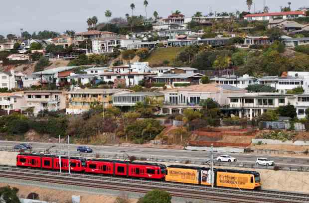 A Blue Line trolley passes homes in western Clairemont on Friday, Dec. 27, 2024 in San Diego. (Meg McLaughlin / The San Diego Union-Tribune)