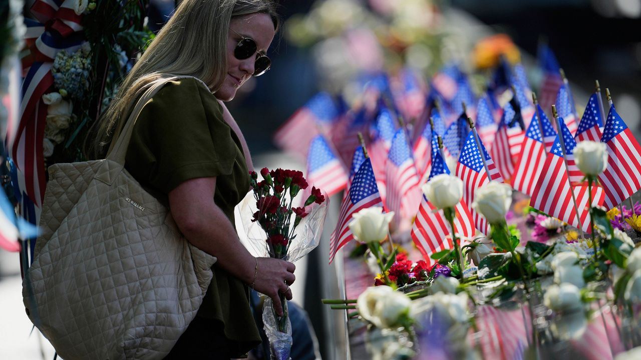 Jaclyn O'Connor places flowers on the 9/11 Memorial during a ceremony to mark the 24th anniversary of the 9/11 attacks, Thursday, Sept. 11, 2025, in New York.  (AP Photo/Seth Wenig)