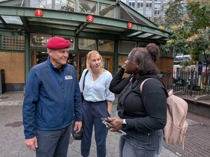 man in a red beret standing next to two woman outside a train station