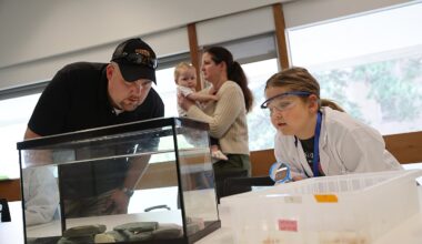 Six-year-old Marianne Cullen examines axolotls in the Harvard lab of Jessica Whited on Sept. 15, 2025. At left is her father, Robert Cullen, baby sister Emmaline Cullen, and mother Kat Demetrion. Marianne loves the salamanders and raised $1,000 to support the lab's work.