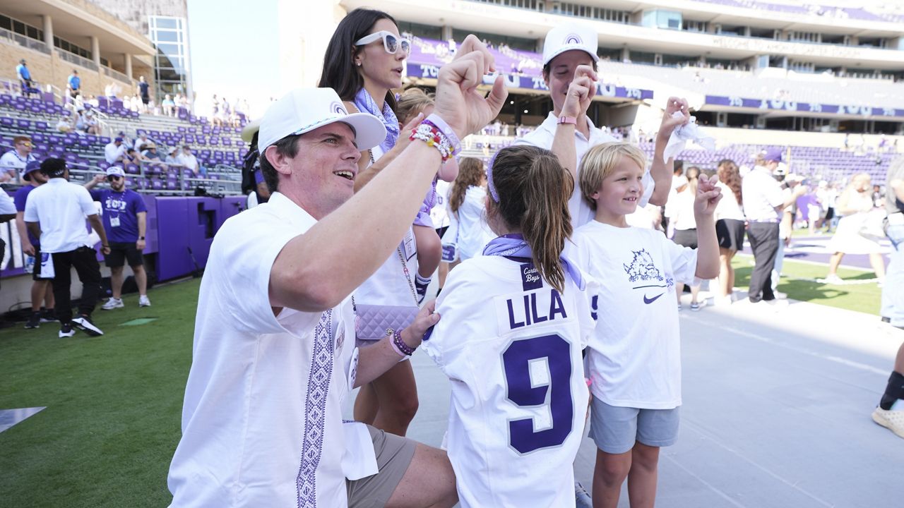 Blake Bonner, left, his wife Caitlin, left rear, standing and their daughter, front, wearing a shirt with her late sisters name stand in the end zone before an NCAA college football game between SMU and TCU, Saturday, Sept. 20, 2025, in Fort Worth, Texas. (AP Photo/Tony Gutierrez)