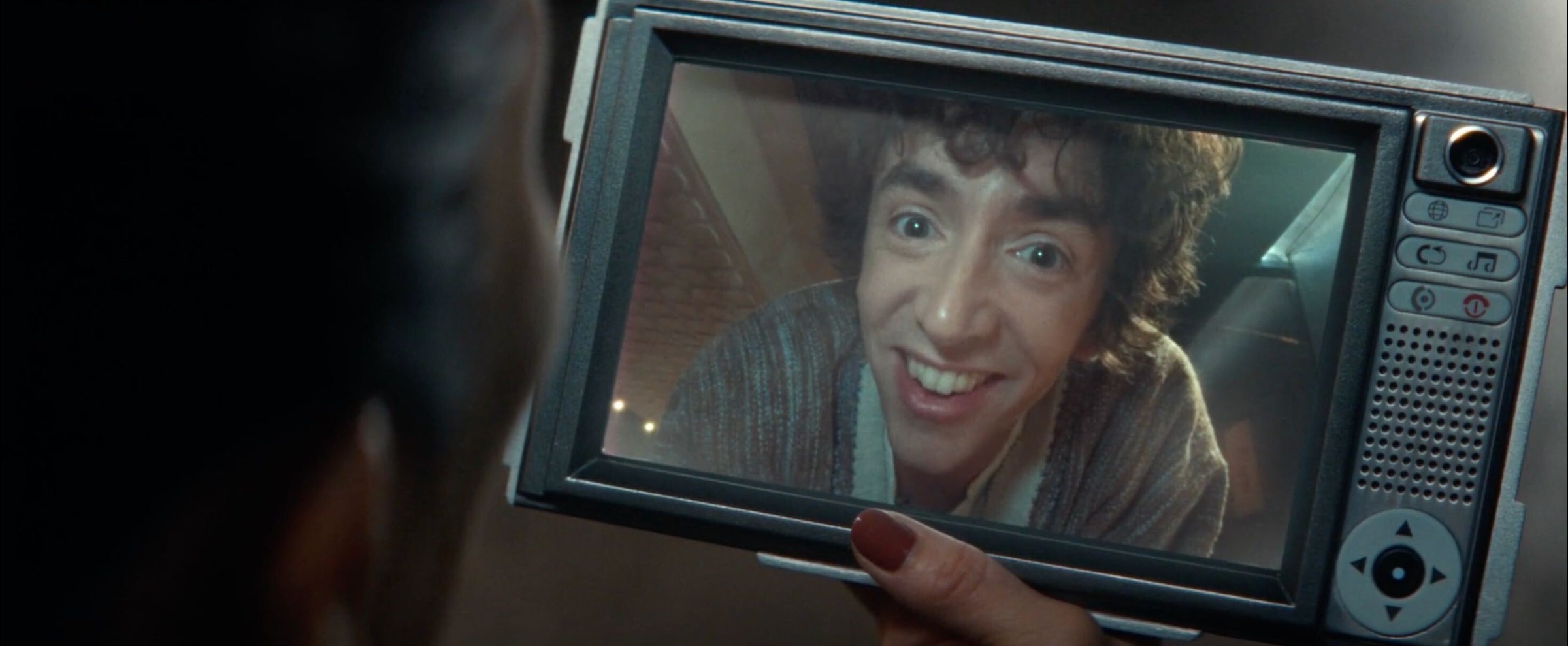 A shot of a woman holding a chunky tablet while having a video call with a grinning man displayed on the screen.