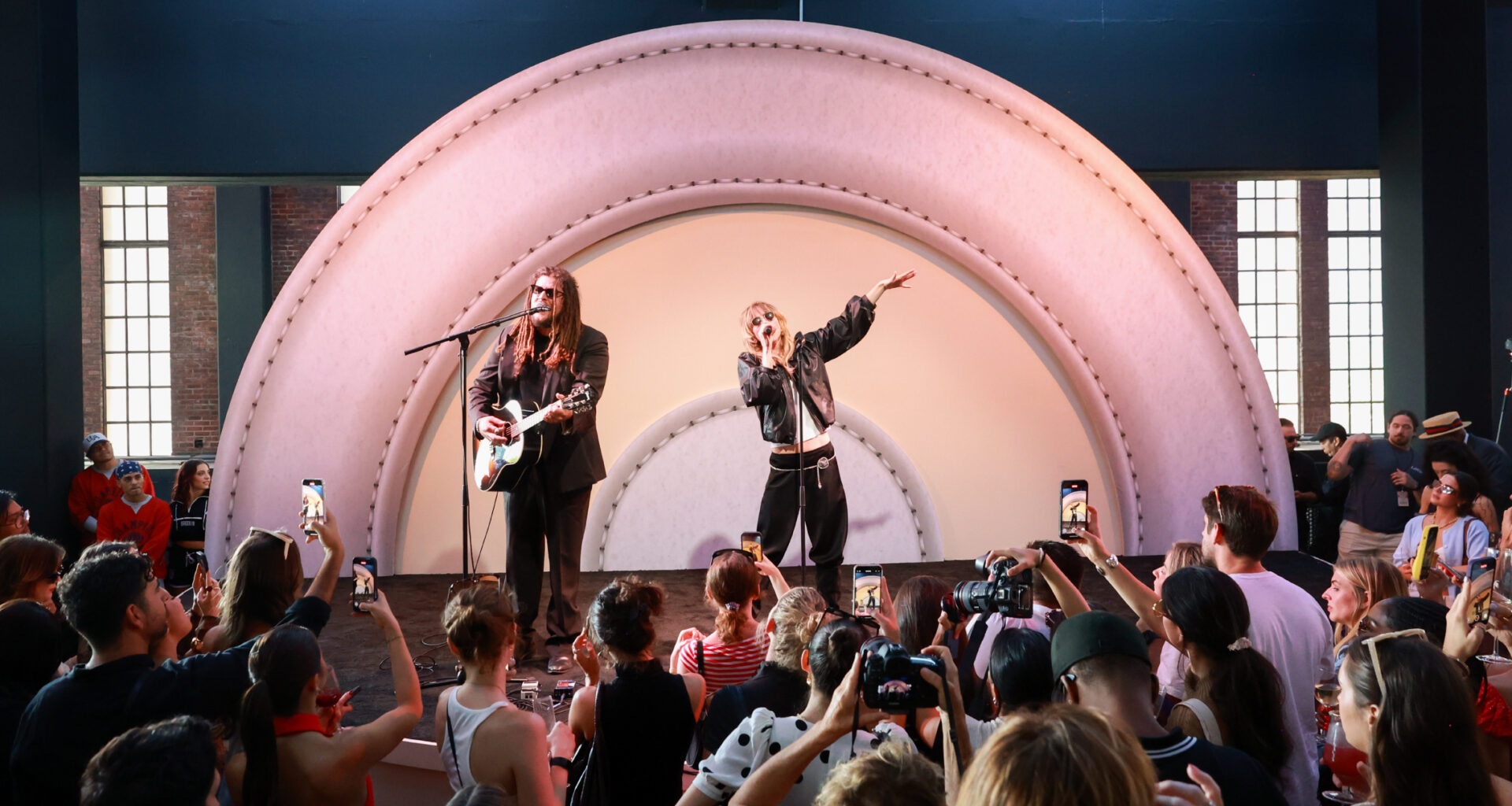 Two people stand on a stage, one sings while the other plays guitar and sings. Behind them is a Target logo.