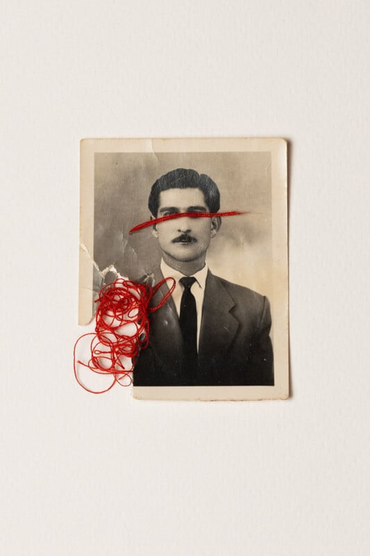 A vintage black-and-white portrait of a man in a suit and tie has a red thread sewn across his eyes, with a tangled bundle of red thread attached to the lower left corner of the photo.