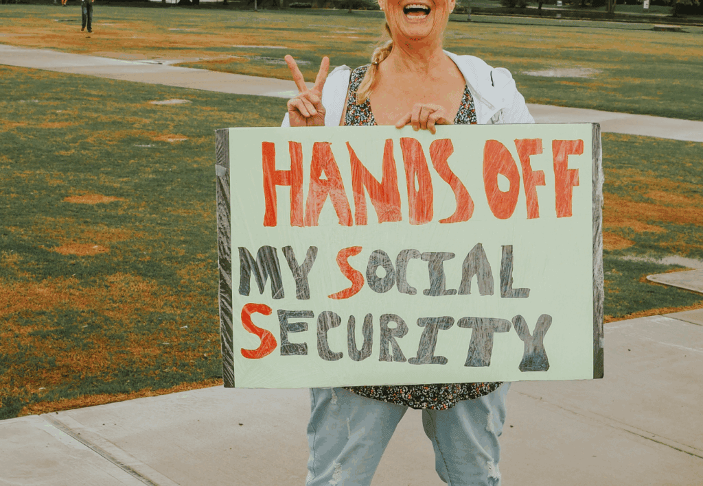 Women holding sign that reads "HANDS OFF MY SOCIAL SECURITY" - Federal Reserve rate cut announcement 2025
