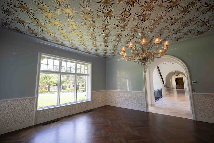 The bold dining room of 4400 Belfort Place features glossy lacquer walls and gold starbursts...