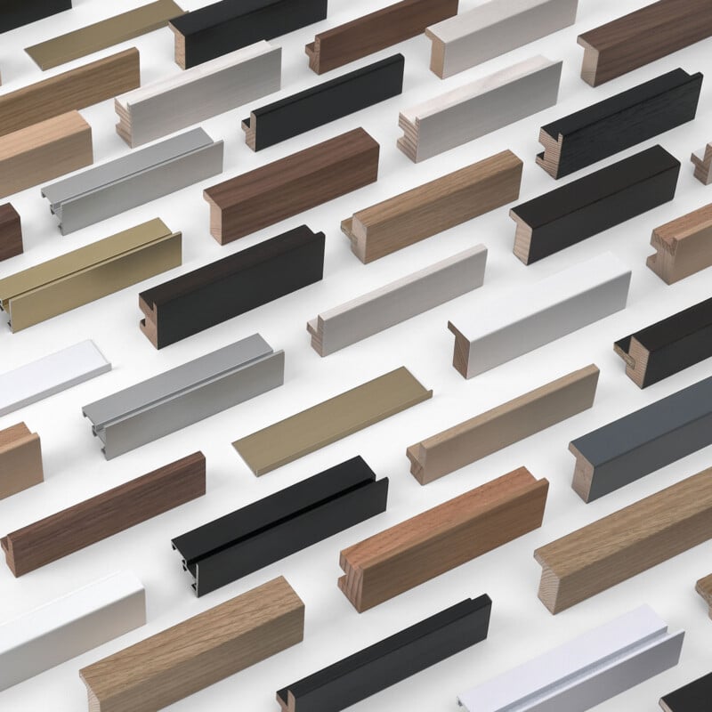 A variety of rectangular wooden, metal, and plastic trim samples in different colors and finishes are arranged diagonally on a white surface.