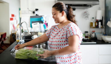 Woman in kitchen removing vegetables from a plastic wrapper