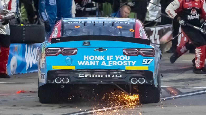 A NASCAR race car with yellow rookie stripes pulling into the pit lane