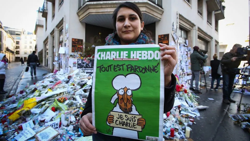 A woman poses with her copy of the French satirical magazine 'Charlie Hebdo' in front of the 'Rue Nicolas Appert' on January 14, 2015 in Paris, France. - Marc Piasecki/French Select/Getty Images