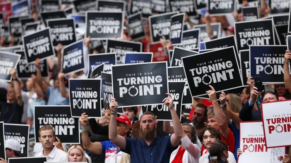 Attendees hold up Turning Point USA signs at the memorial service for political activist Charlie Kirk at State Farm Stadium on September 21, 2025 in Glendale, Arizona. - Eric Thayer/Getty Images