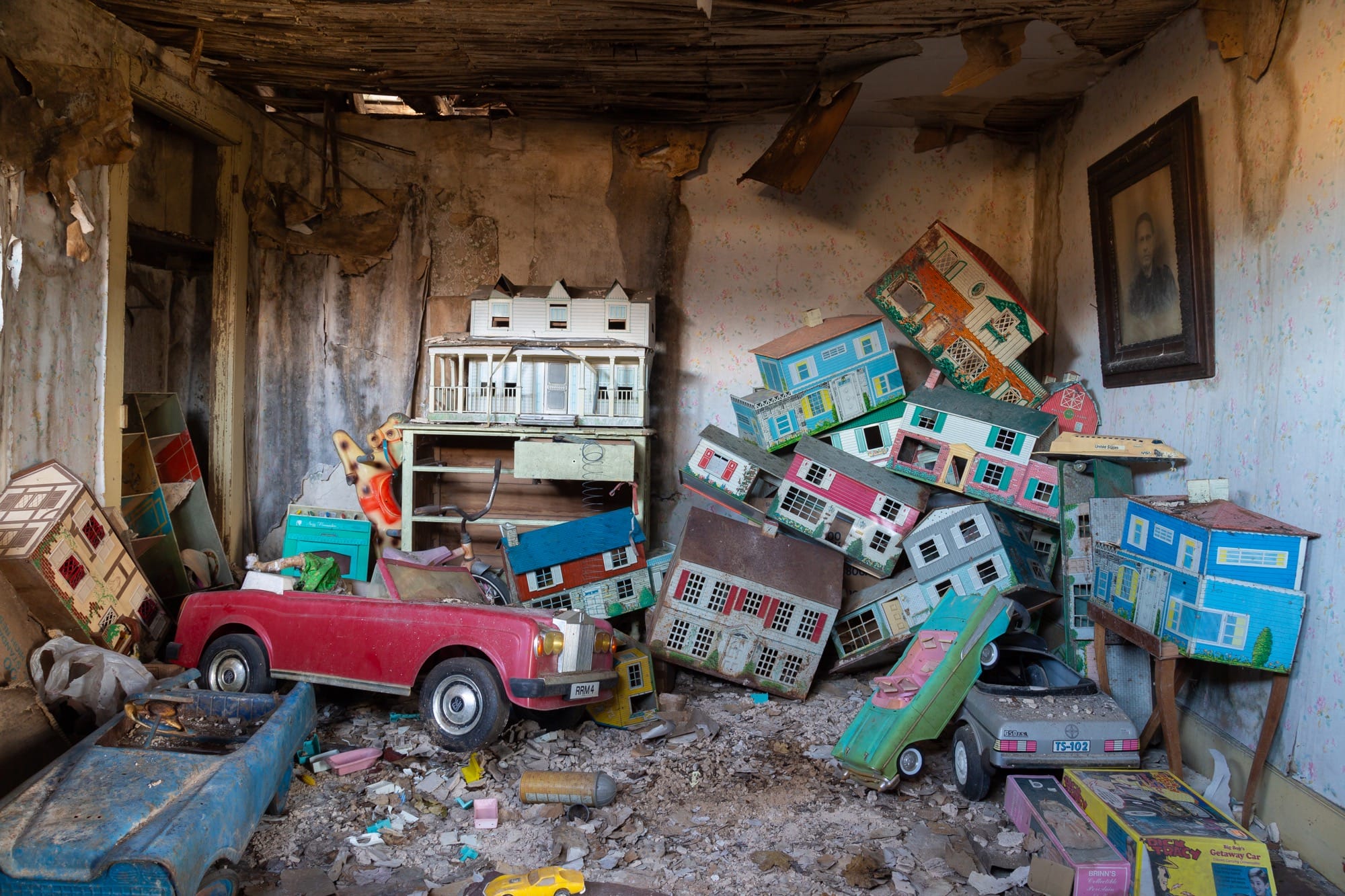 a photo of a room with stacks of dollhouses and toy cars inside an abandoned house by Bryan Sansivero