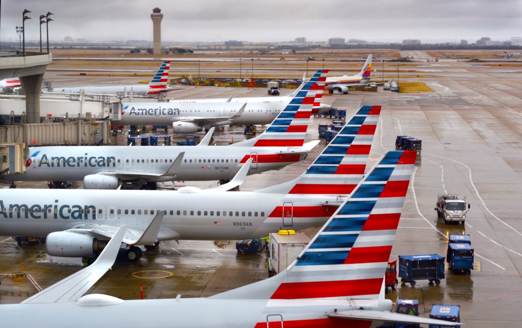 American Airlines passenger jets parked at gates on a rainy morning at Dallas/Fort Worth International Airport.