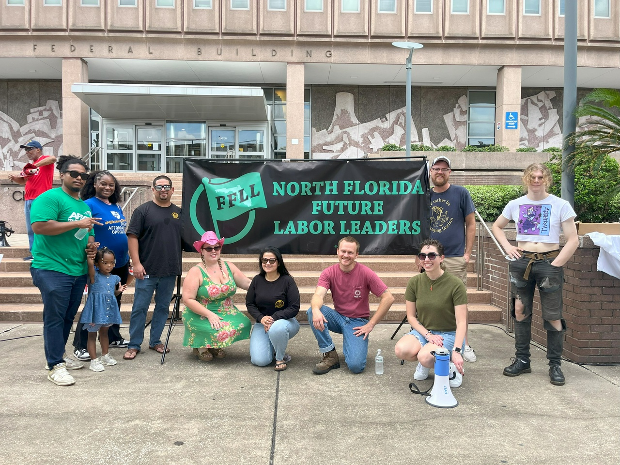 A group of protesters pose in front of a banner that says, "North Florida Future Labor Leaders" at a Labor Day protest.