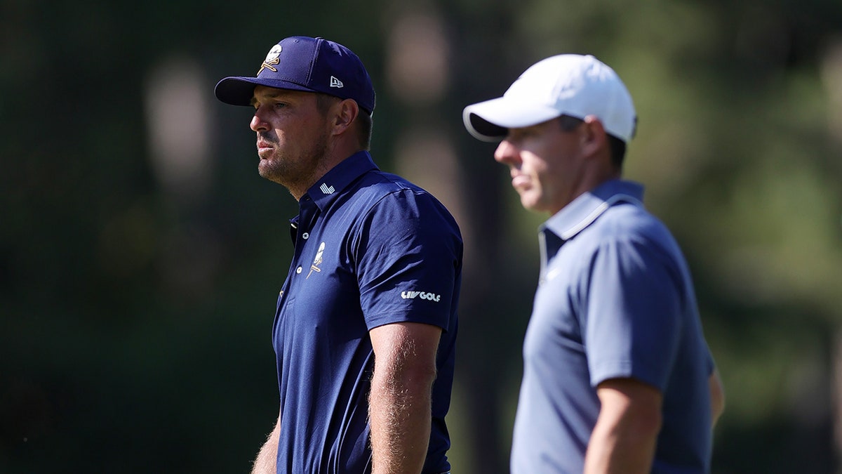 Bryson DeChambeau and Rory McIlroy look on course