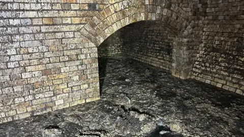 SWW A brick built historic sewer with and arched chamber full of large amounts of fat and grease that has built up. 