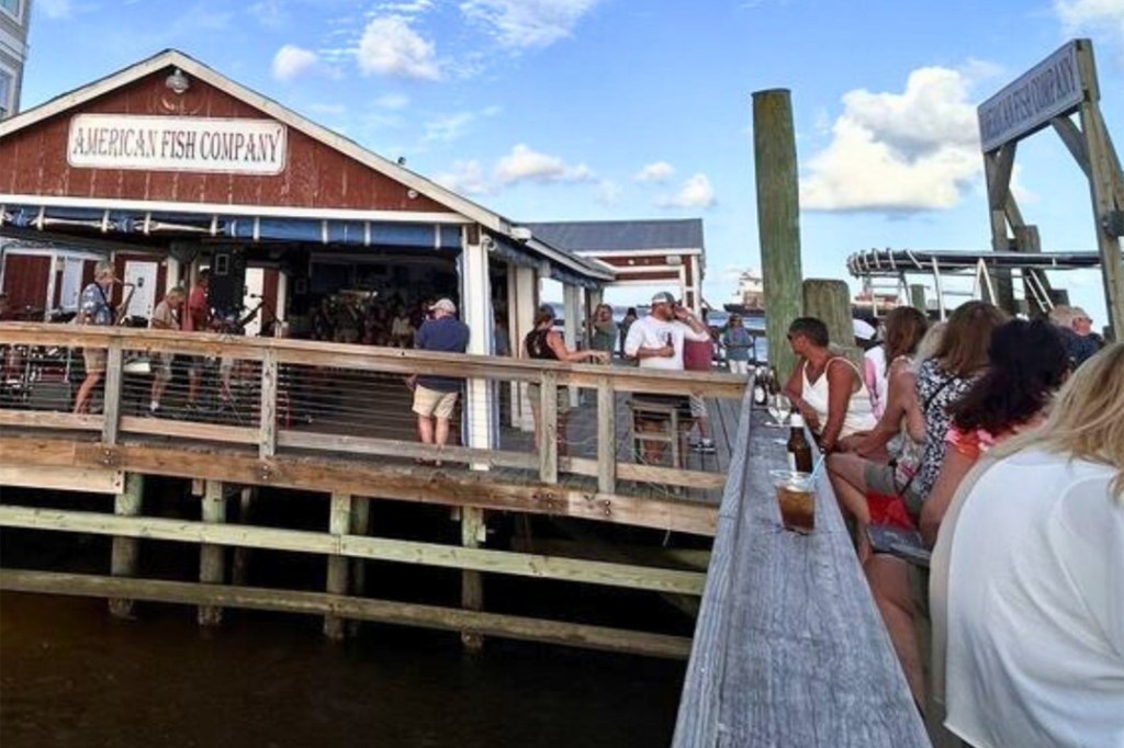People enjoying drinks and conversation on the deck of the American Fish Company restaurant.