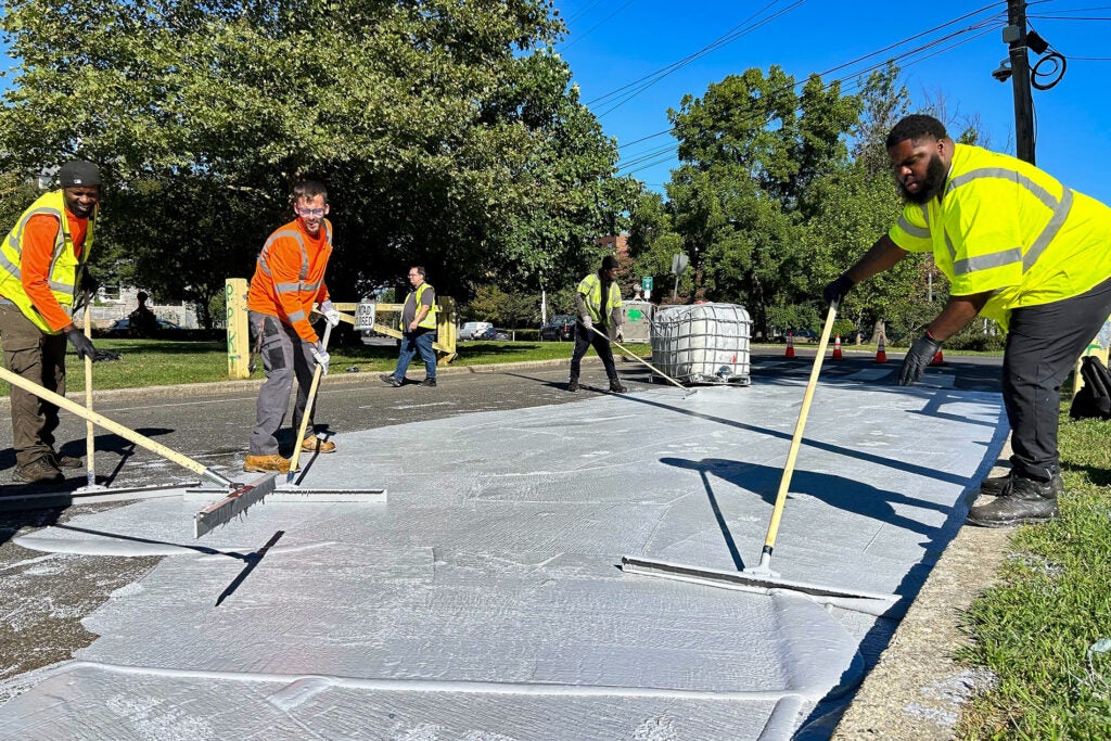 Workers spread the white coating along the road