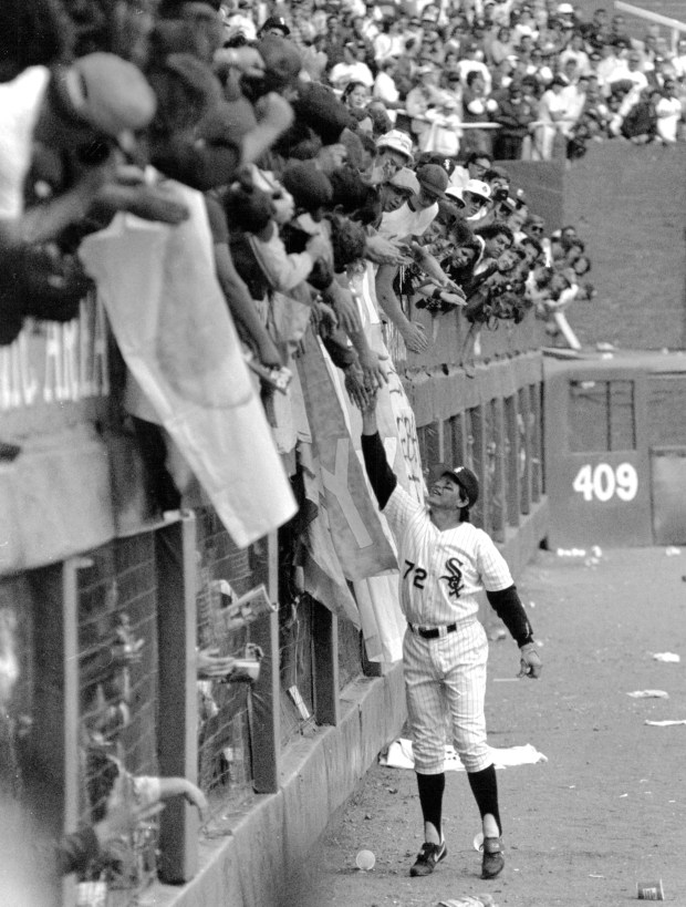 White Sox catcher Carlton Fisk reaches up on his tiptoes to shake the outstretched hands of fans in the left field bleachers at Comiskey Park after the game against Seattle on Sept. 30, 1990. It was the last game played at the old Comiskey Park. (Frank Hanes/Chicago Tribune) 
