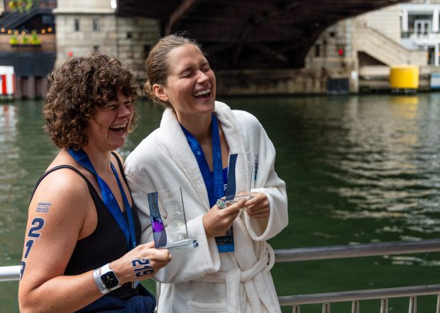Becca Mann, left, of Homer Glen, and U.S. Olympic Swimmer Olivia Smoliga, of Glenview, laugh together while posing for a picture after they raced in the Chicago River Swim on Sept. 21, 2025. Mann placed first in the female no-wetsuit 2-mile division and held the fastest time for the 2-mile division. Smoliga placed first in the female no-wetsuit 1-mile division. (Dominic Di Palermo/Chicago Tribune)