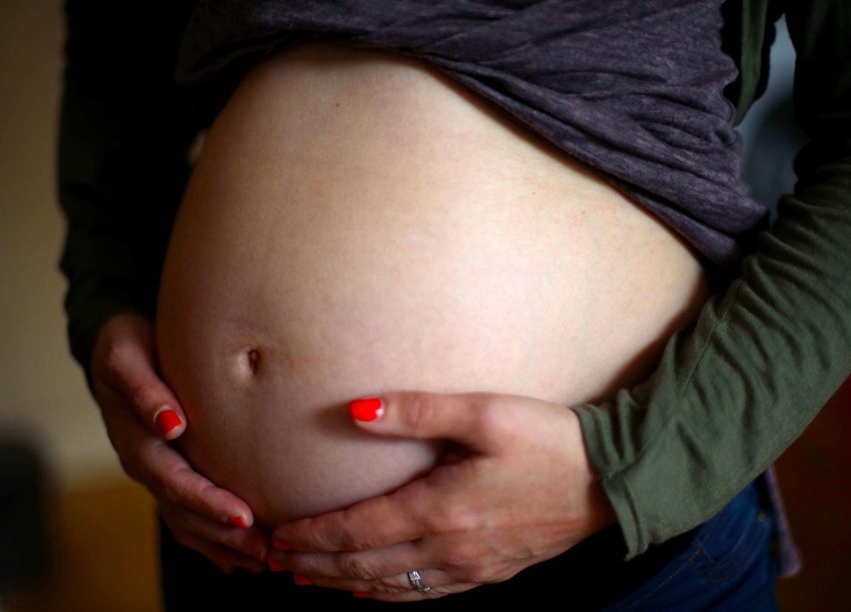 Close up of a pregnant woman holding her stomach.