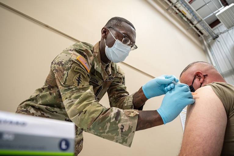 A U.S. military medic administers a Covid-19 vaccine to a soldier.