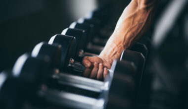 man lifting dumbbell off dumbbell rack
