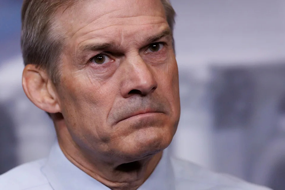 A person with a serious expression is seen in close-up, looking slightly away from the camera