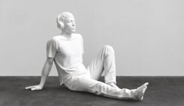 a sculpture by Elmgreen and Dragset of a white figure resting on the floor wearing headphones