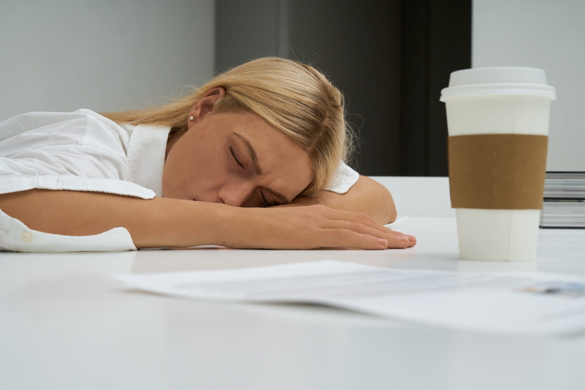 an installation by Elmgreen and Dragset of a realistic looking blond woman slumped over at her desk