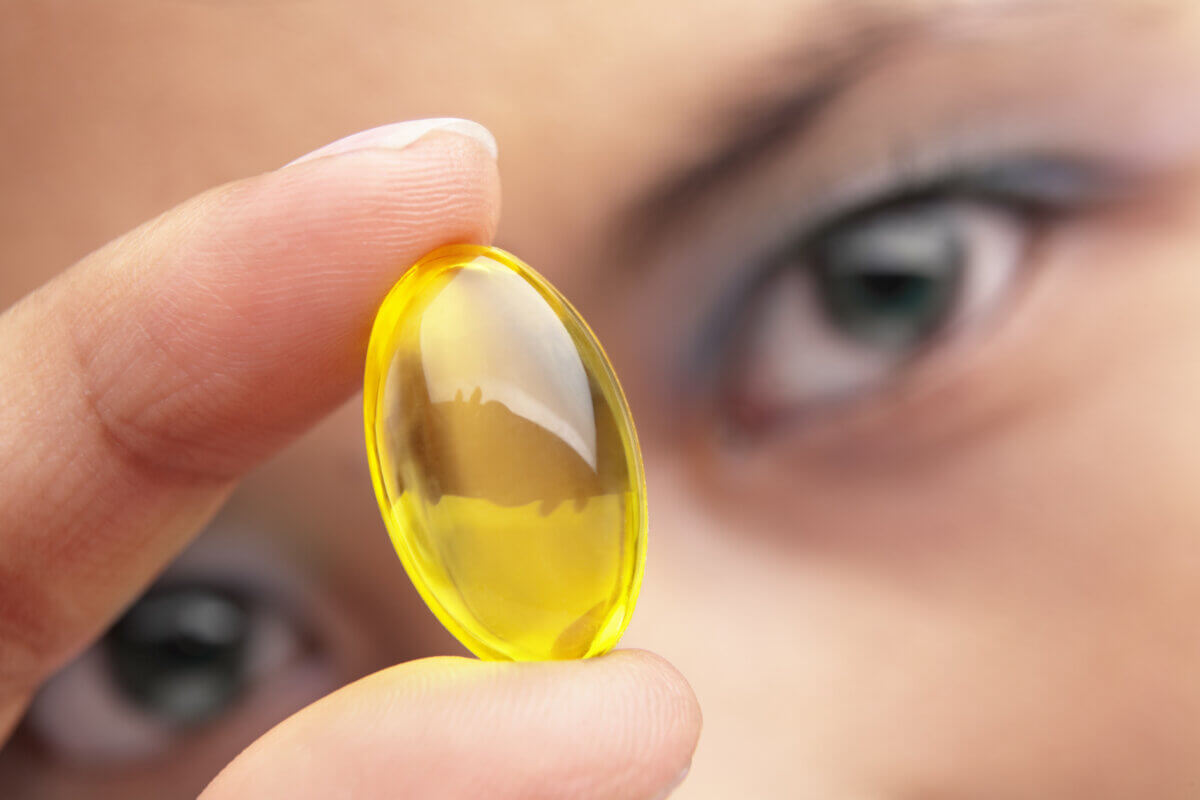 A woman holding a yellow vitamin capsule