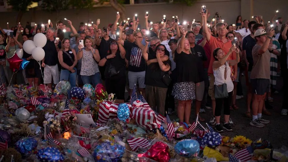 People visit a makeshift memorial for Charlie Kirk outside Turning Point USA headquarters on September 20 in Phoenix, Arizona. - John Locher/AP