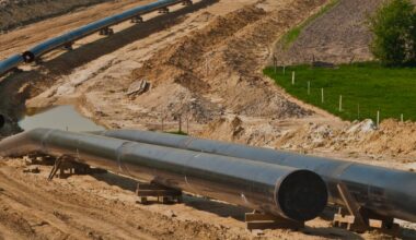A silver pipeline runs over light brown dirty.