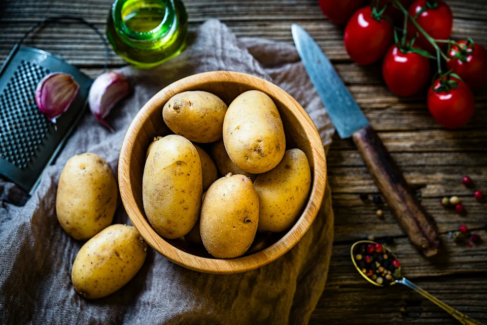 Bowl filled with raw fingerling potatoes shot from above on rustic table.