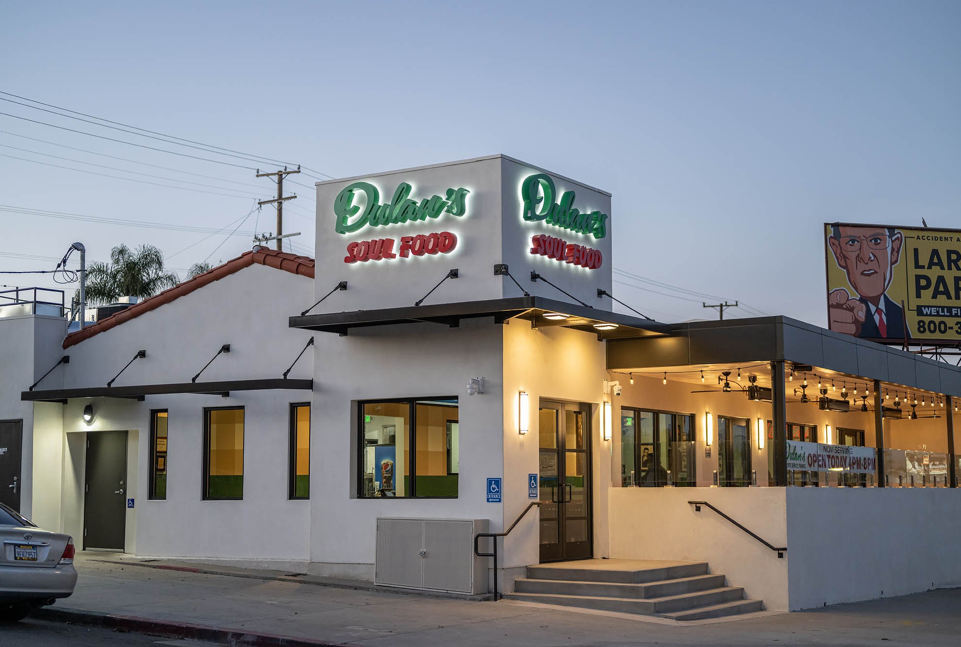 A corner view of a white painted restaurant building with green and red lettering at Dulan’s on Crenshaw in Los Angeles.