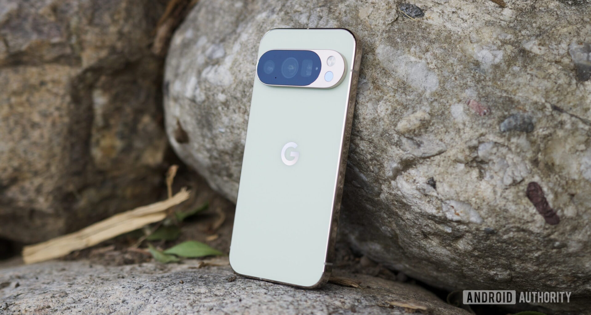 The Google Pixel 10 Pro in Jade, laying up against a rock.