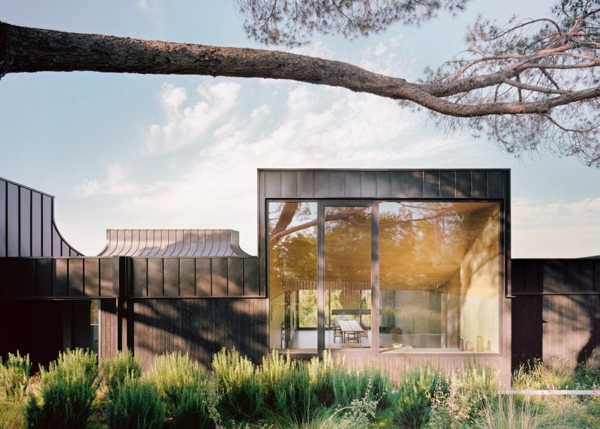 Exterior of a home with blackened wood and metal cladding around a large window