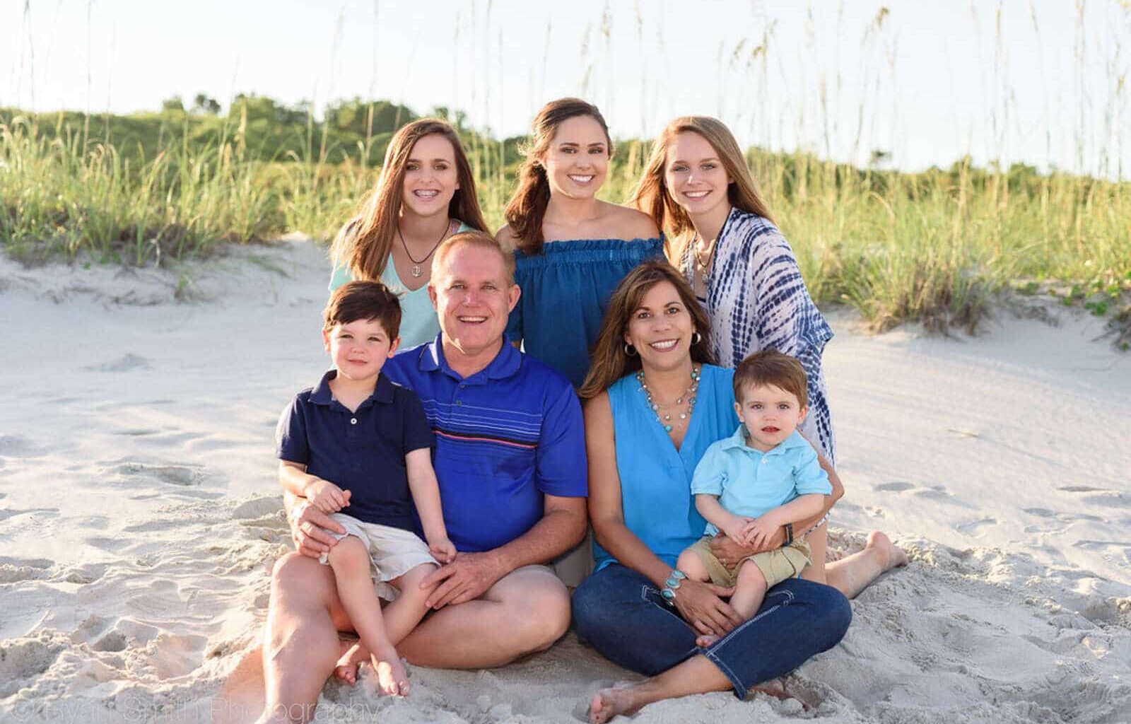 Image of a family sitting and posing for a photo at the beach