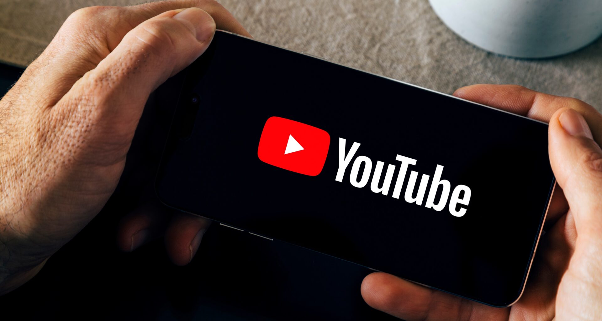 Man holding a smartphone with the YouTube app opening