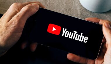 Man holding a smartphone with the YouTube app opening