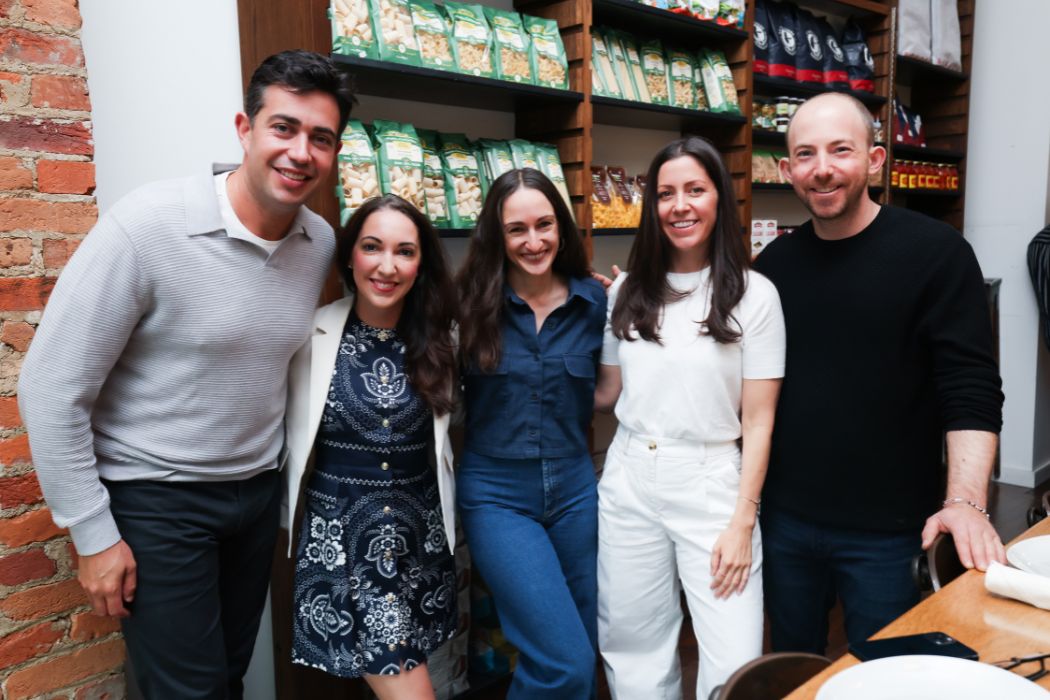 A group of people stand arm-in-arm, smiling.