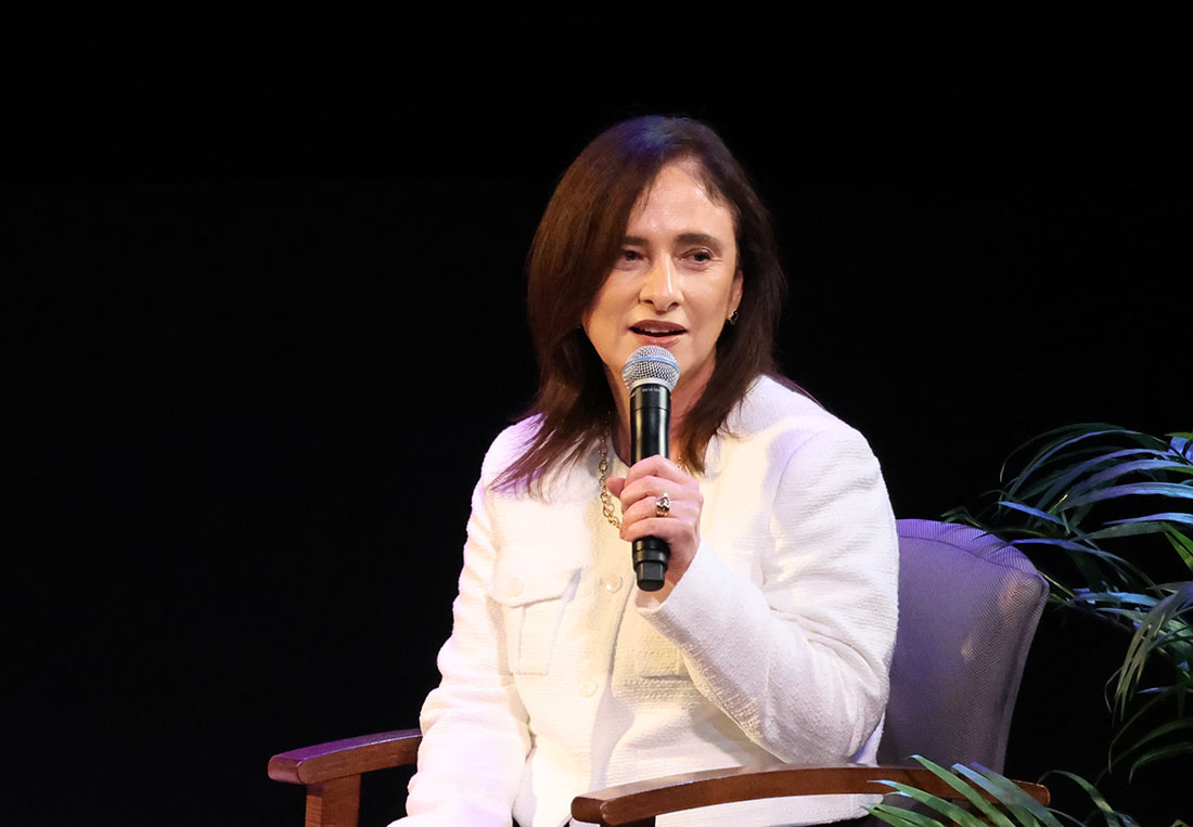 Dr. Alejandra Perez speaking through a microphone onstage at the cancer summit