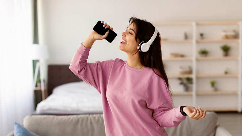 A woman sings into her smartphone microphone.